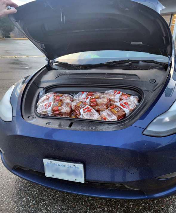 A blue Tesla front trunk full of loaves of whole wheat bread