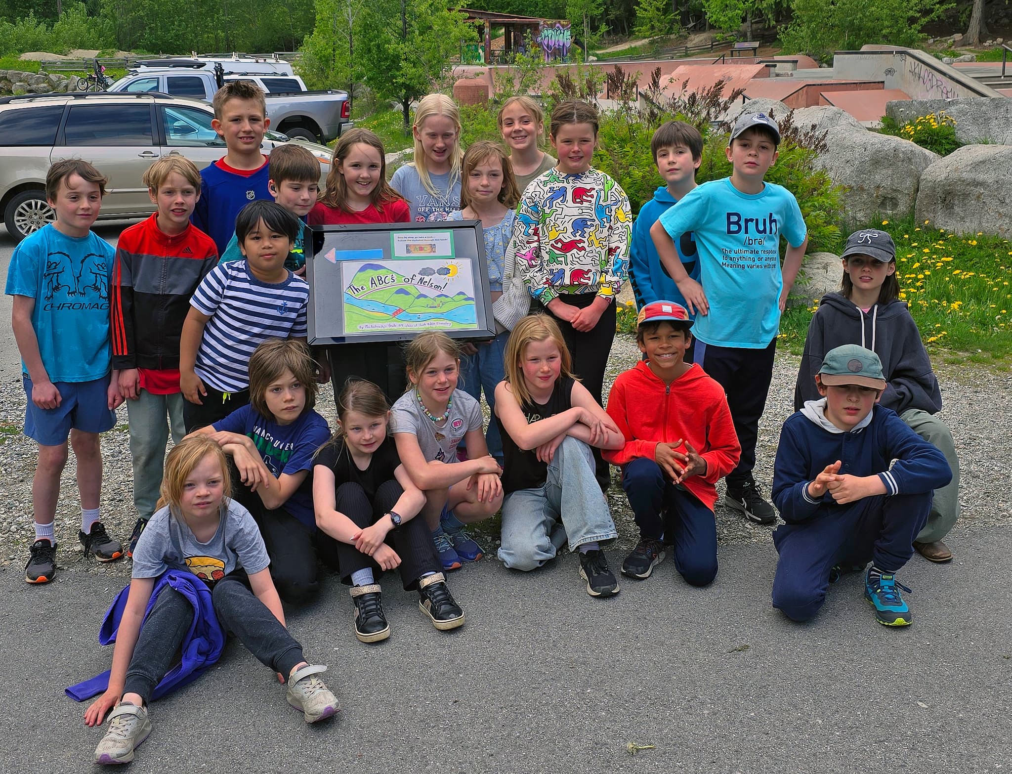 A group of elementary school students pose in front of a display board in a park