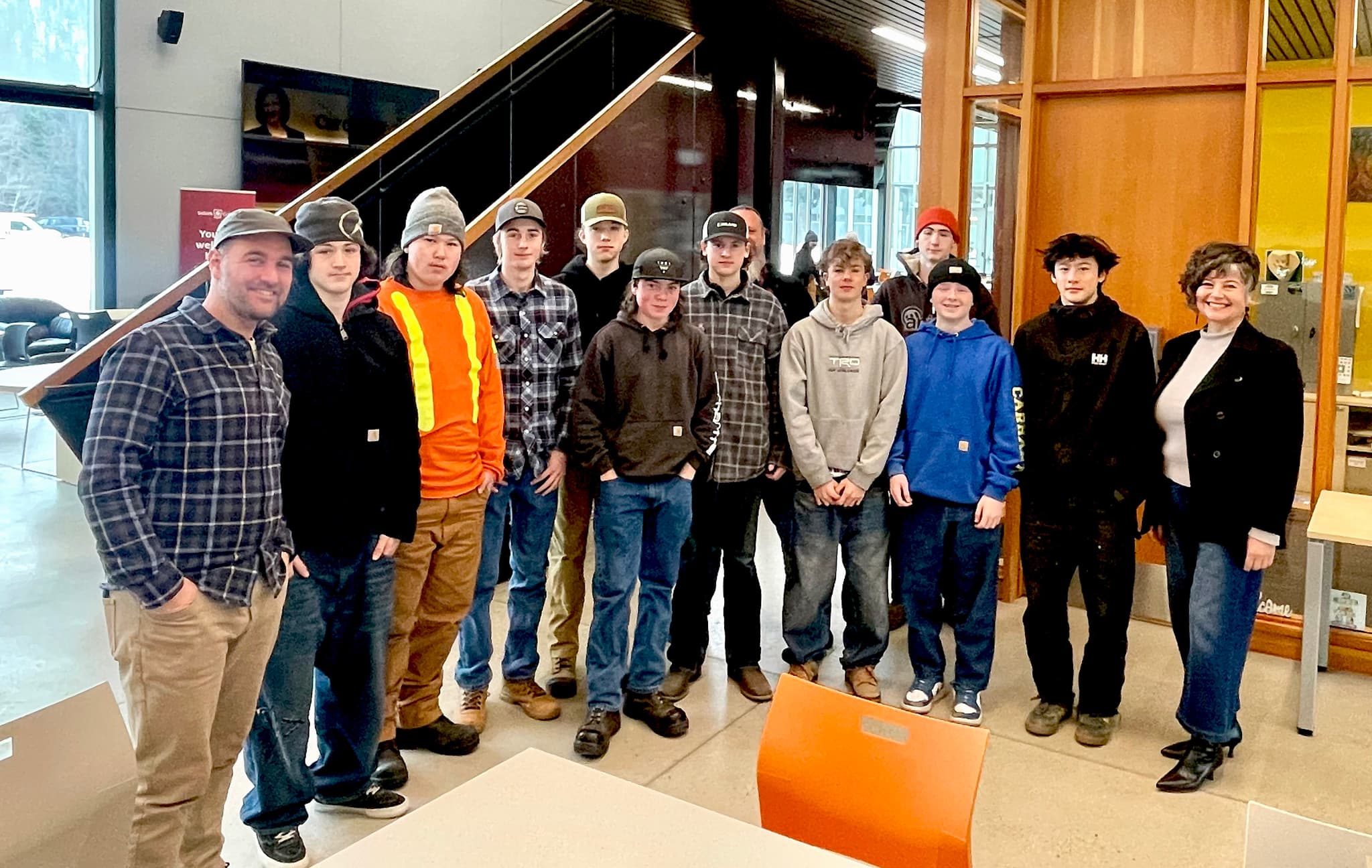 A trades teacher stands with a group of teenaged trade students in a college setting.