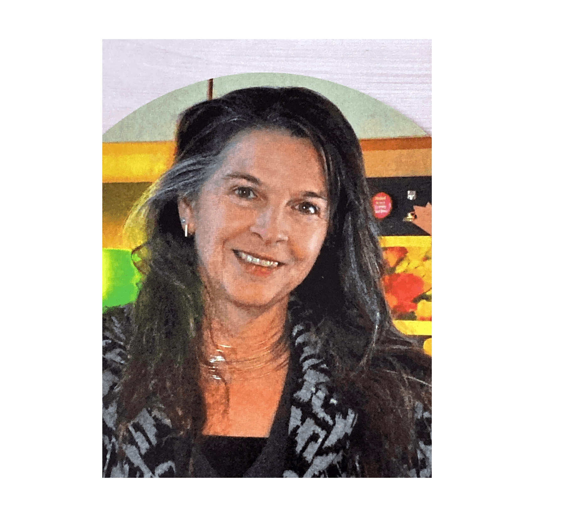 A head and shoulders shot of a smiling woman with long salt and pepper hair