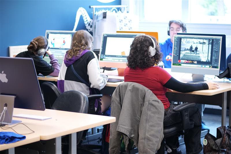 Students seated at desktop computers in a classroom.